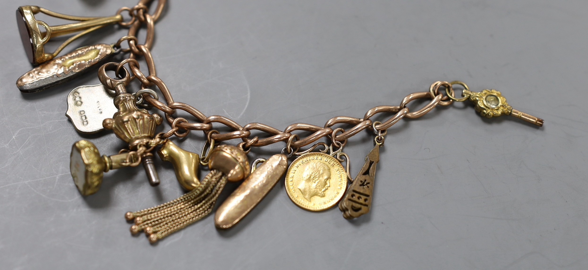 A 9ct charm bracelet, hung with assorted charms including two 9ct, silver and enamel, gilt metal and two gold coins gross weight 61.4 grams.